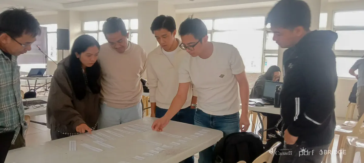 Participants collaborate around a large printed map during a GIS exercise.