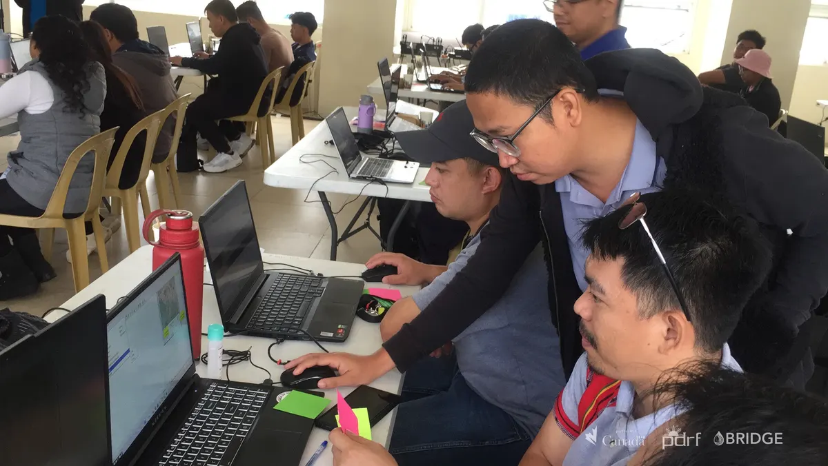 Participants analyze geospatial data on laptops.