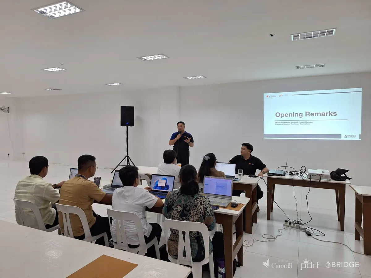 BRIDGE Program Manager Alex Czar Masiglat delivering opening remarks to participants seated at laptops during the Basic GIS training in Antipolo.